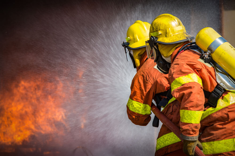 two firefighters spraying high pressure water to fire