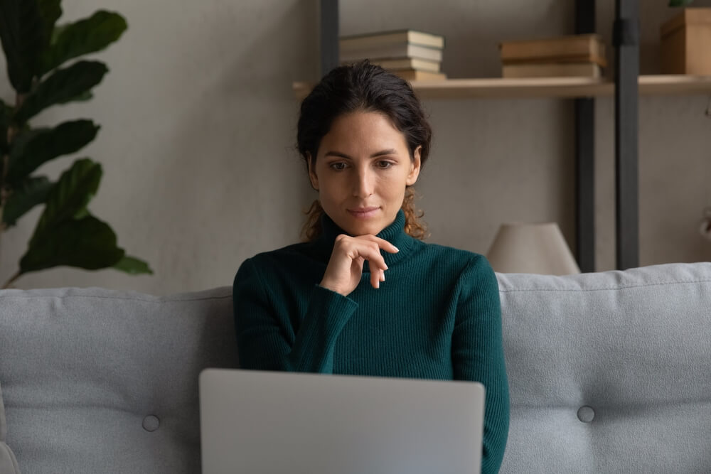 woman infront of her laptop with her hand under her chin