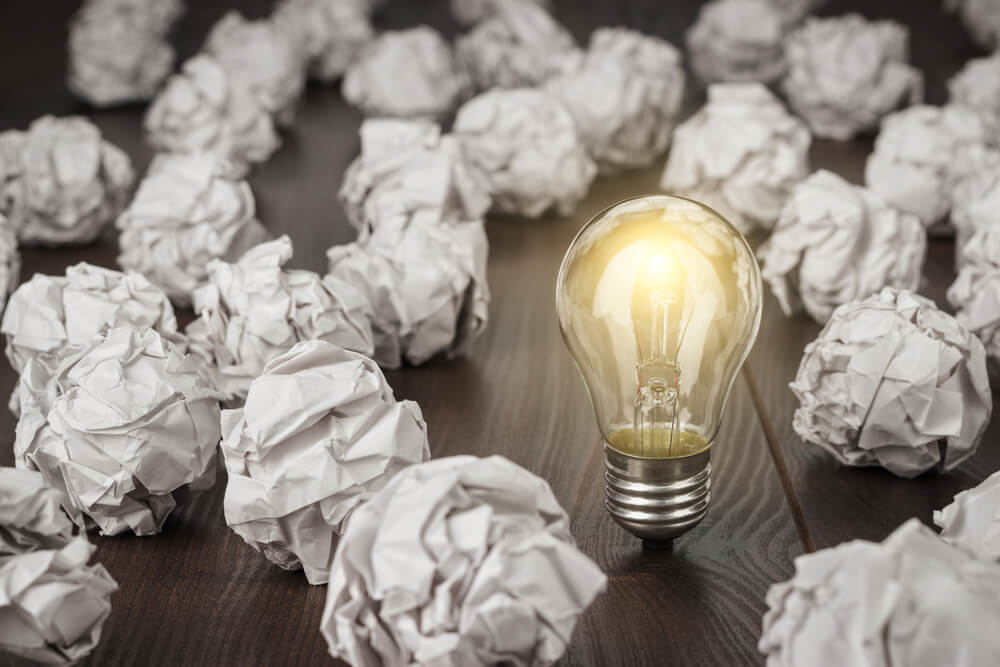 light bulb surrounded by crumpled papers