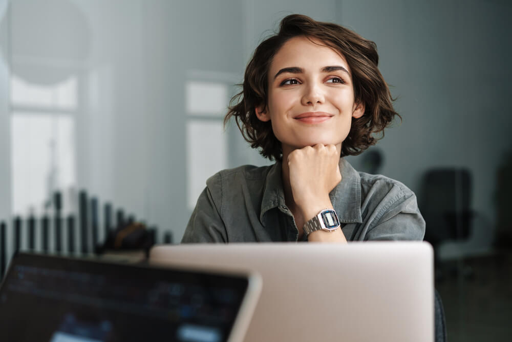 woman smiling and looking on the side while using laptop