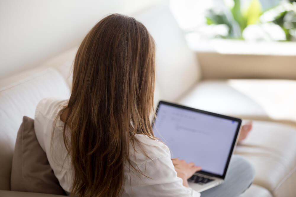 back view of woman typing a resume on her laptop