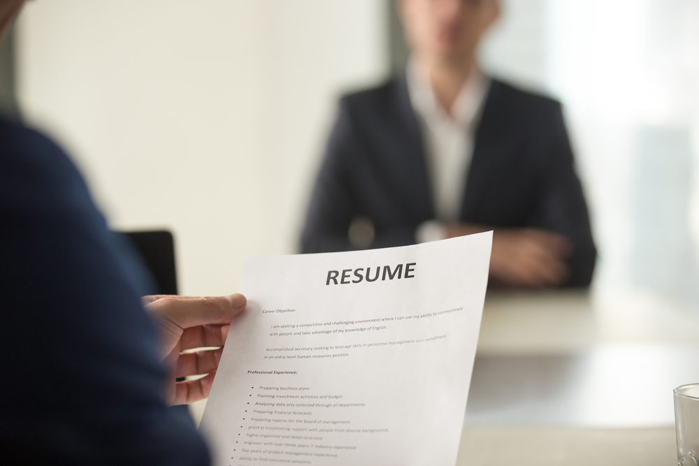 recruiter reading resume in front of female applicant