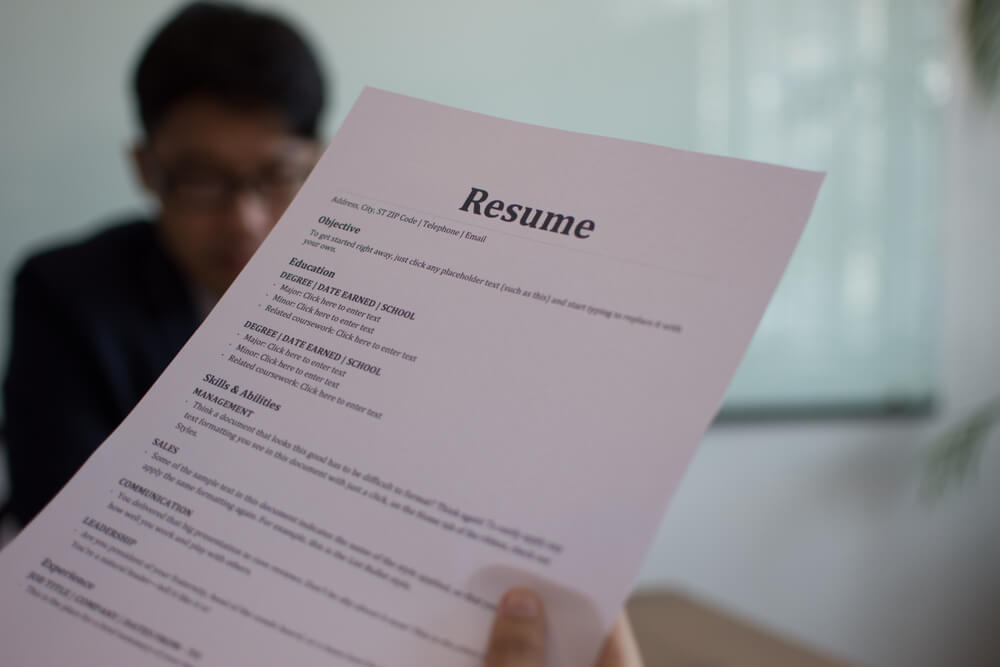 recruiter holding a resume while in front of a job candidate