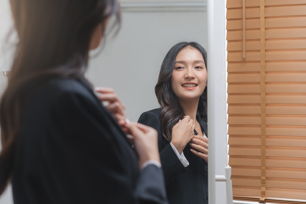 female employee looking in the mirror on formal suit